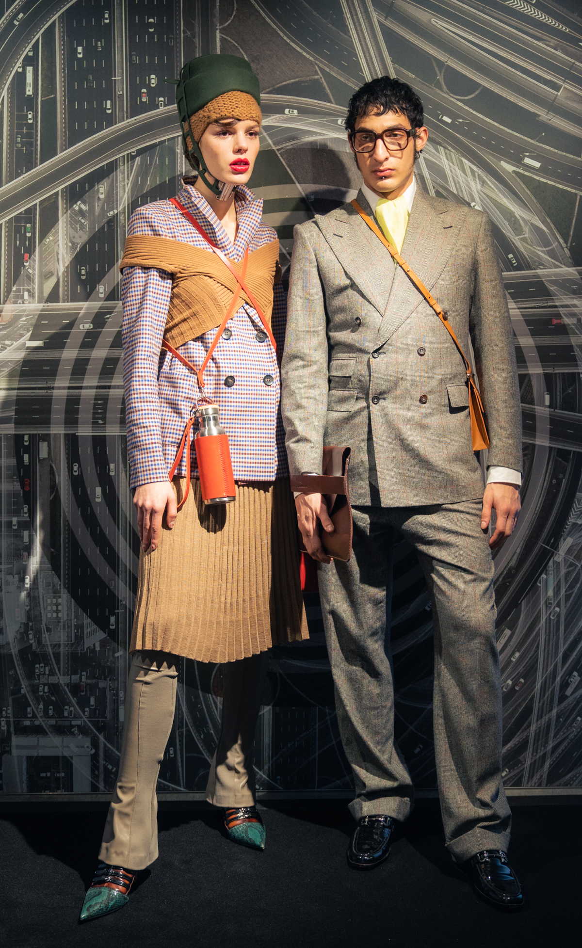 Two models wearing a blazer by Lanius, trousers & skirt by Fassbender, top by Studio Fantastique, knitted hat by Pugnat, hat by Spatz Hutdesign, bag & bottle by Trakatan, handbag by Alexandra Svendsen and shoes Miu Miu at Nightboutique Archive as well as a suit, handkerchief & collar by Maximilian Mogg, shirt by G-Star Raw, clutch by Agnes Nordenholz, crossbody bag by Alinaschuerfeld, glasses by Andy Wolf and shoes by Salvatore Ferragamo Vintage at Neonyt Installation