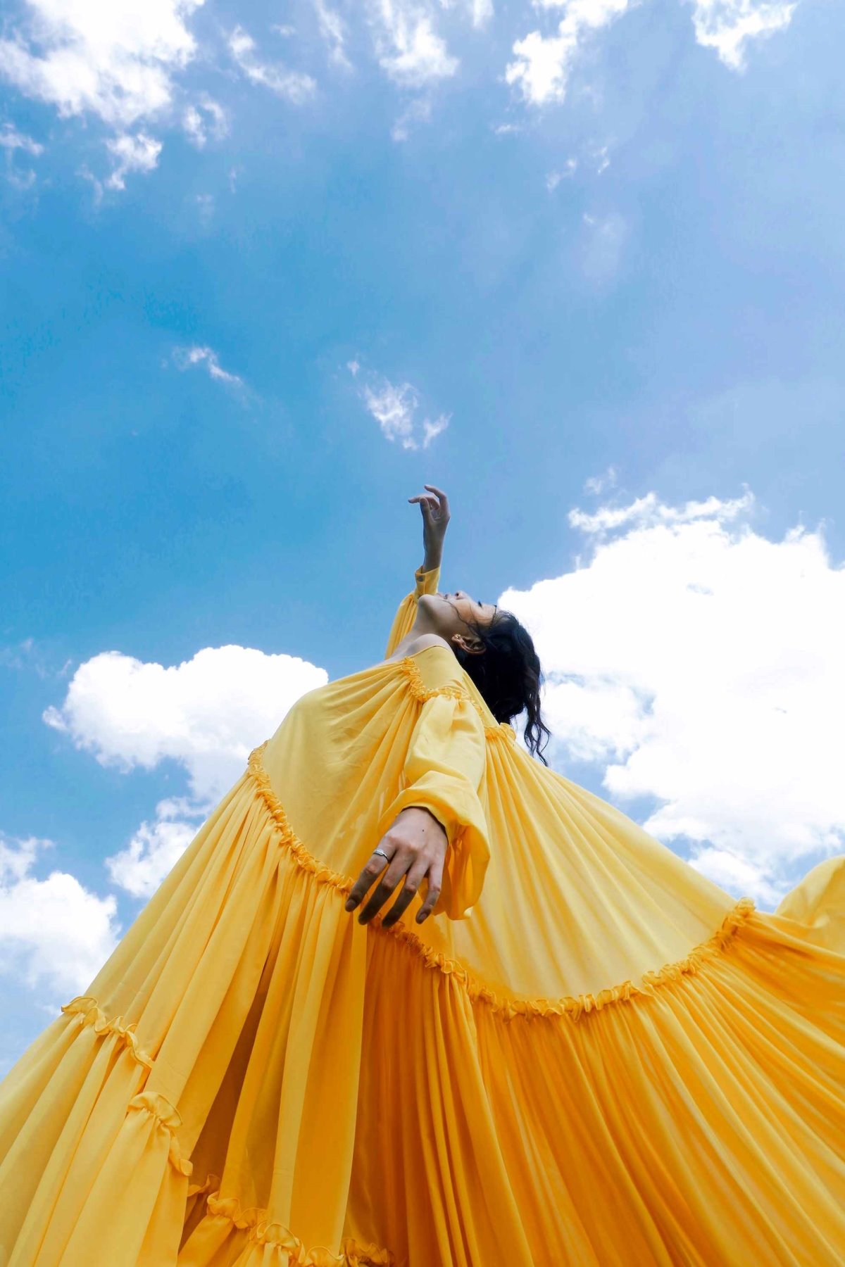 Person Reaching Up To Sky In Yellow Dress. Sustainable Marketplaces.
